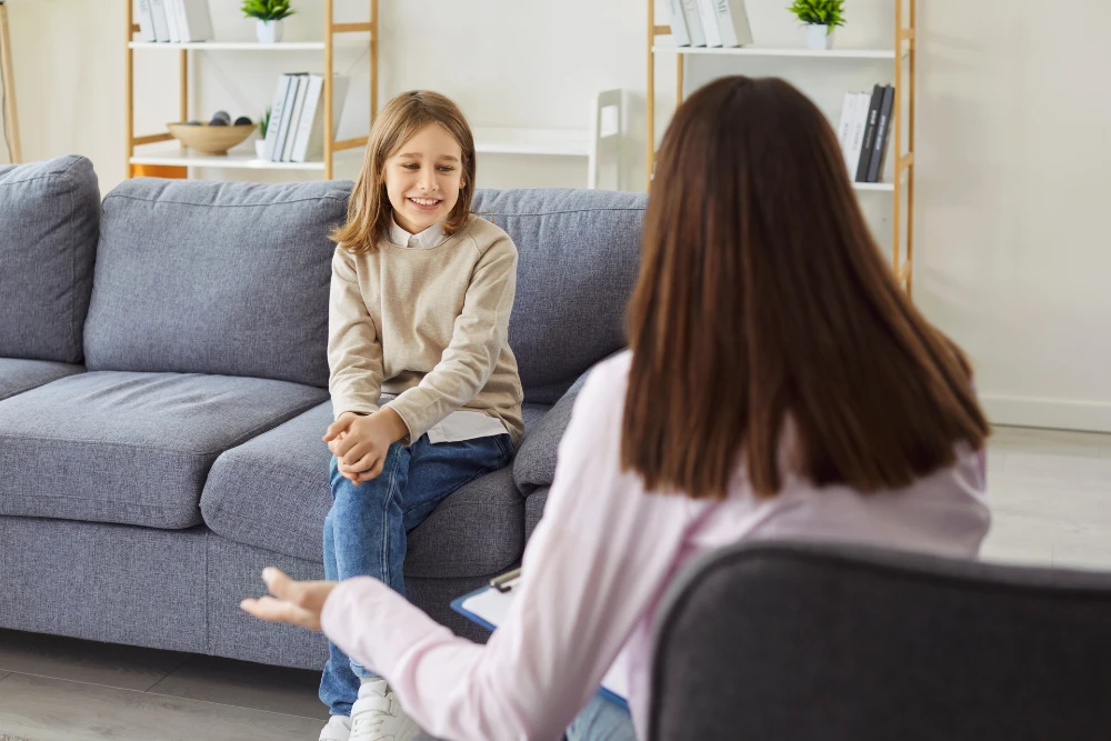 Psycholog rozmawia z&nbsp;uśmiechniętą dziewczynką podczas terapii – psychologia Rybnik